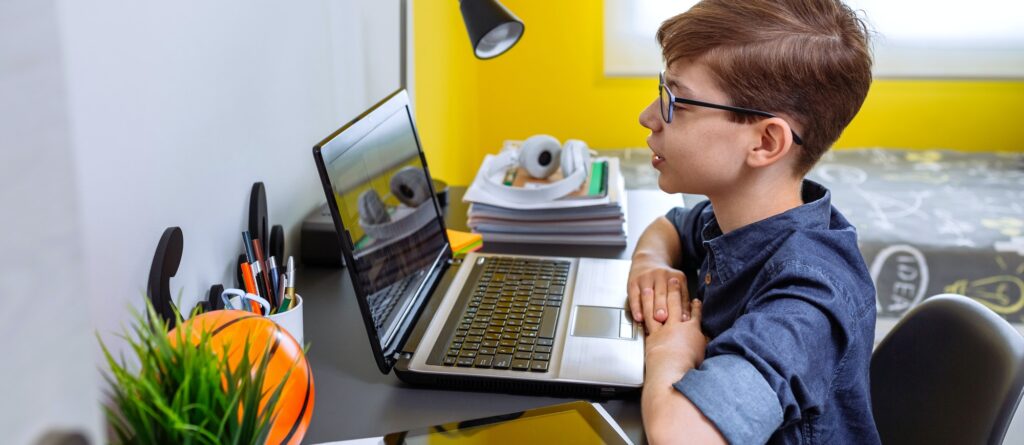 Preteen receiving class at home with laptop from his bedroom